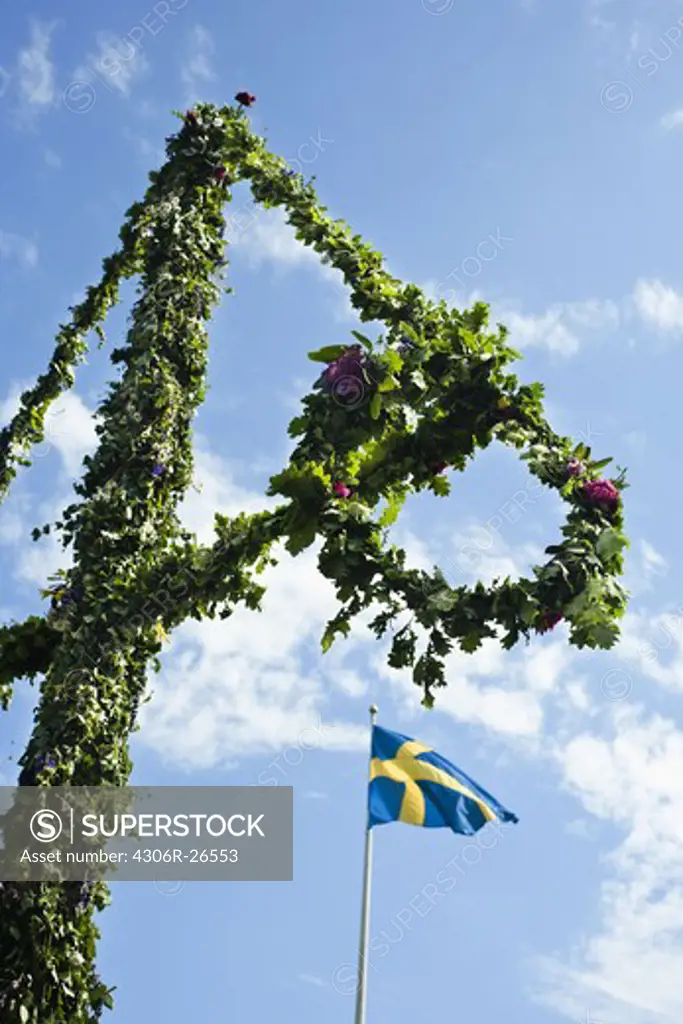 Maypole and Swedish flag against sky