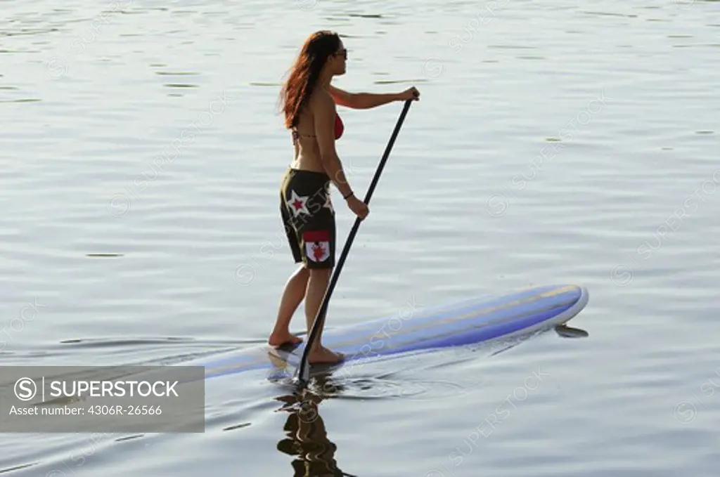 Mid adult woman stand up paddle surfing