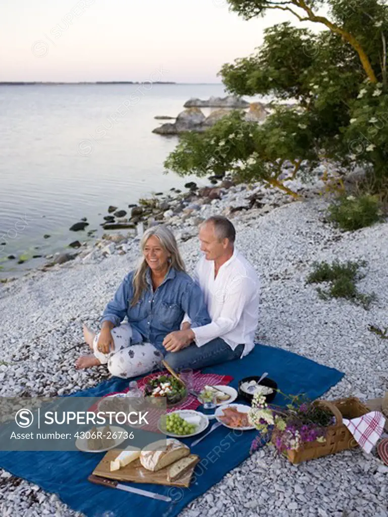 Mature couple having picnic on beach