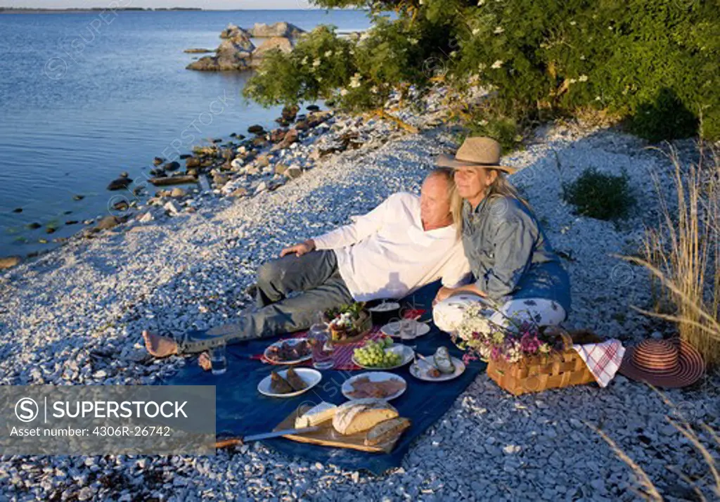 Mature couple having picnic by sea