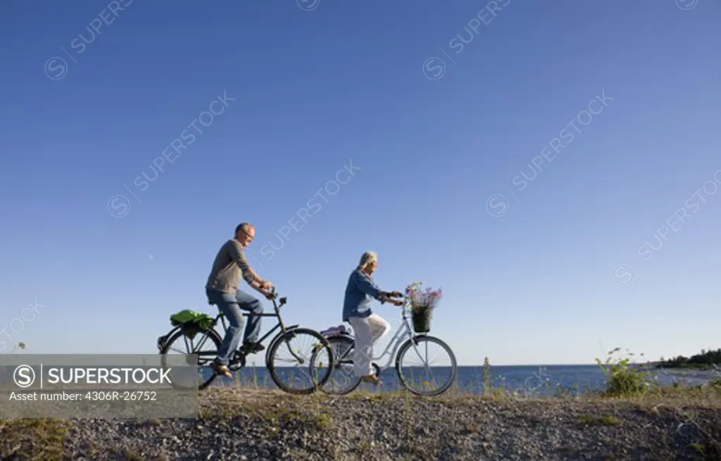 Mature couple riding bicycle on beach
