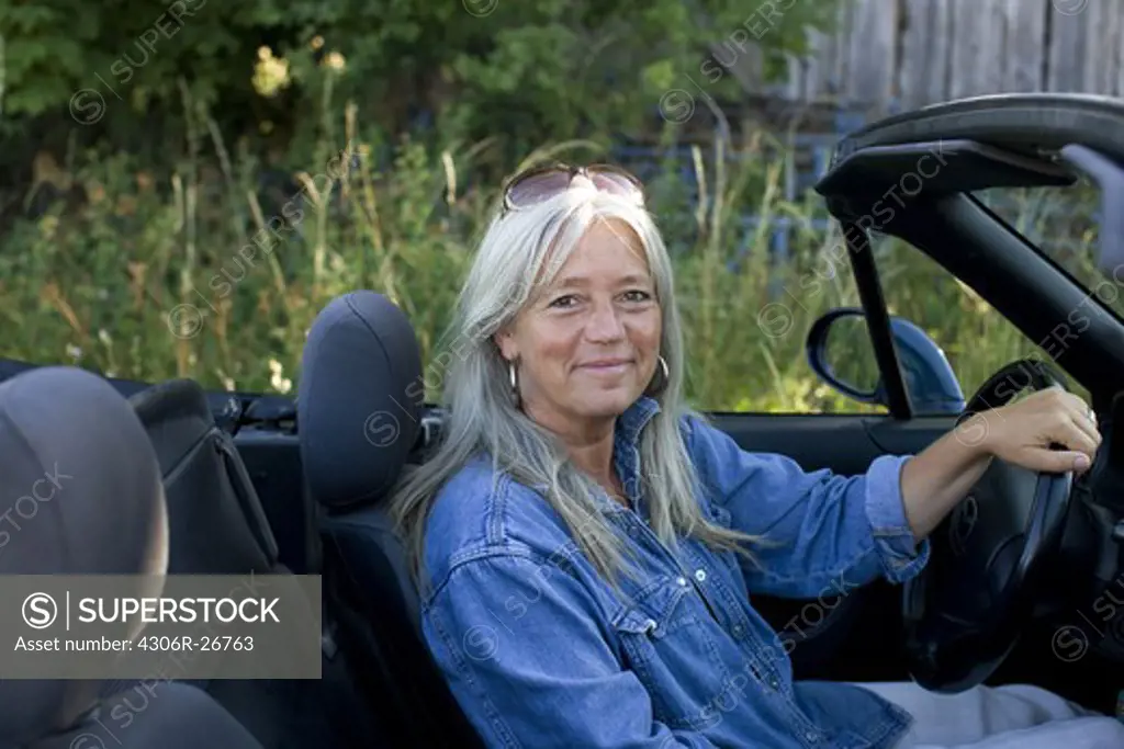 Mature woman sitting inside convertible car