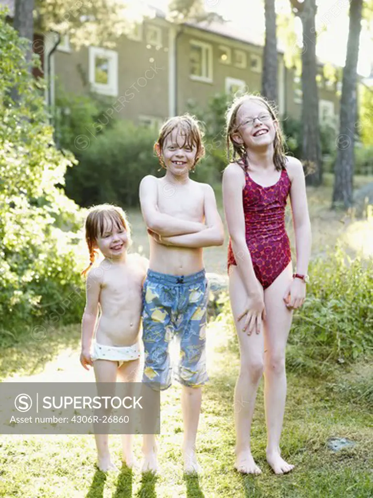 Wet brother and two sister standing in garden