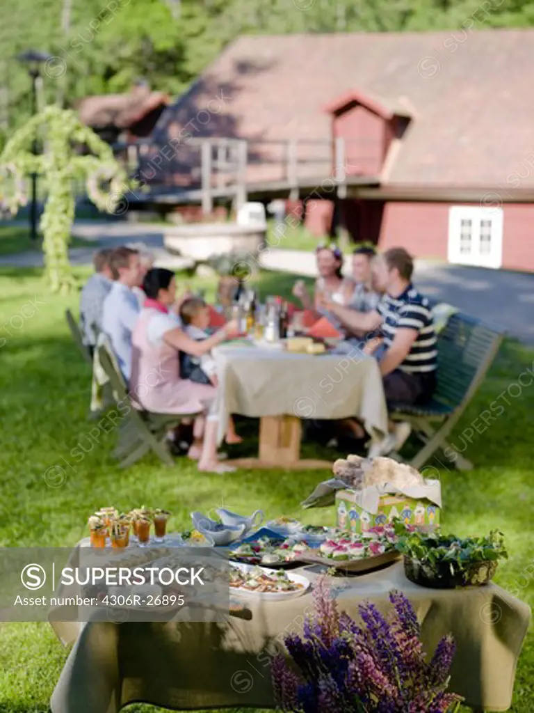 Group of people having midday meal in garden