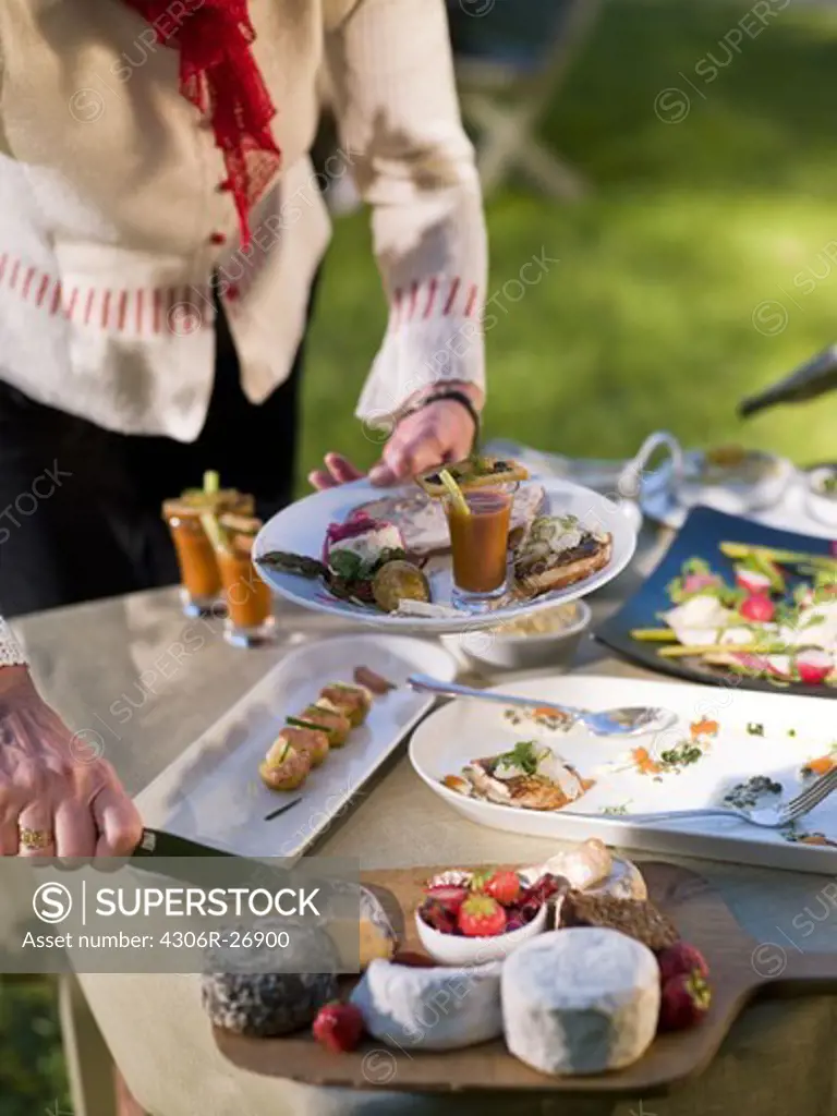 Woman cutting cheese on table in garden
