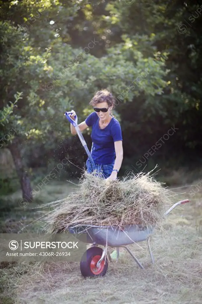 Woman filling wheelbarrow with grass