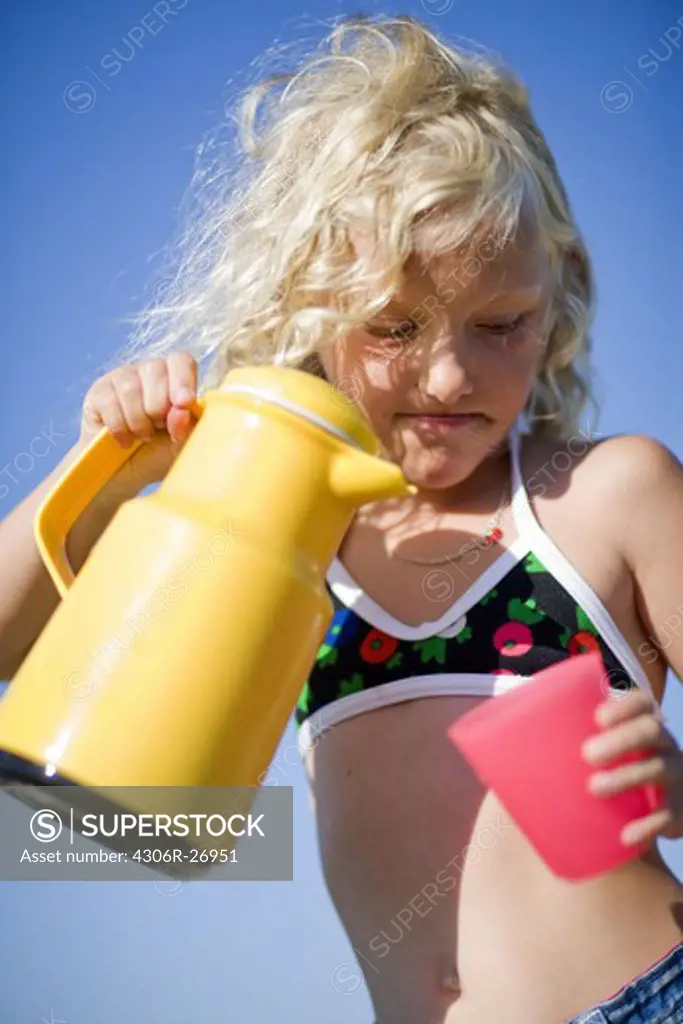 Girl in bikini top holding glass and jug