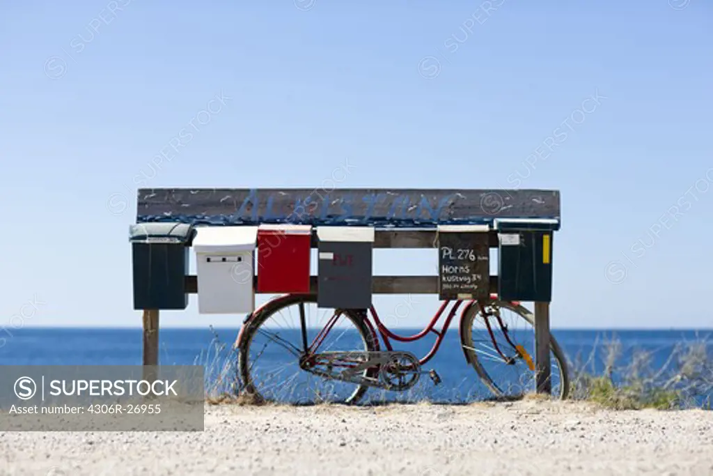 Letterboxes and bicycle with sea in background
