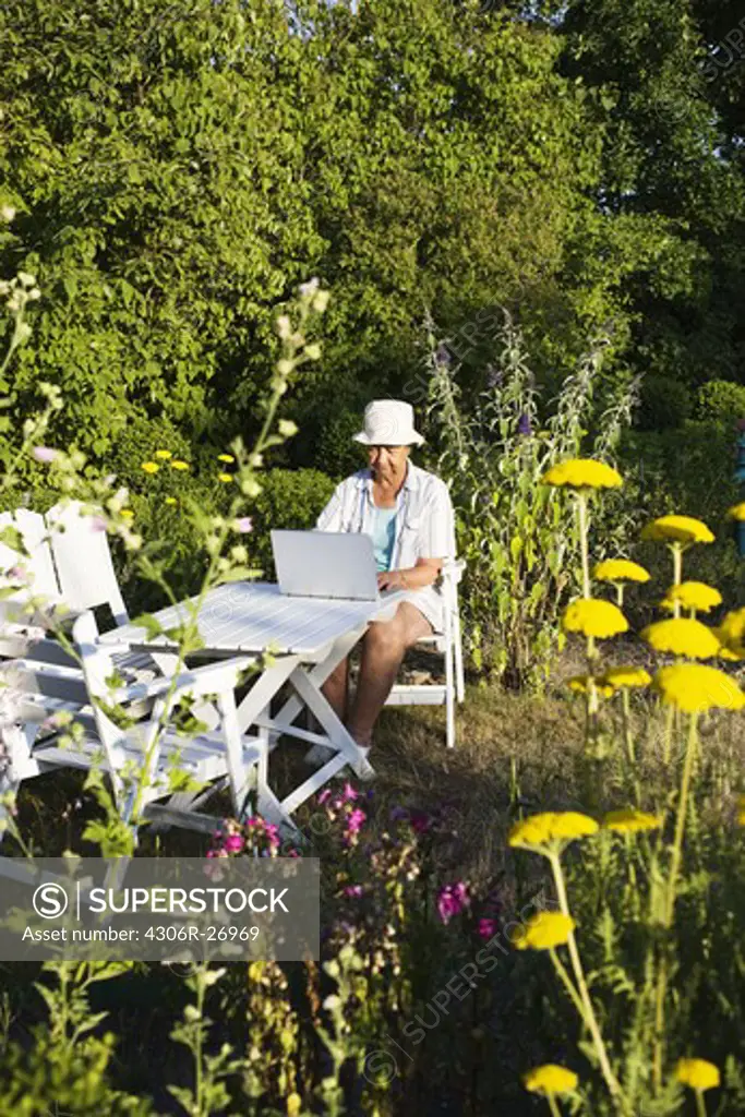 Senior woman using laptop in garden