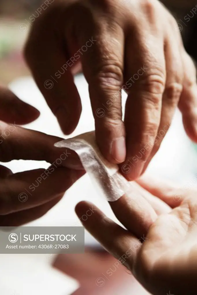 Close-up view of mans hand dressing flash wound of finger