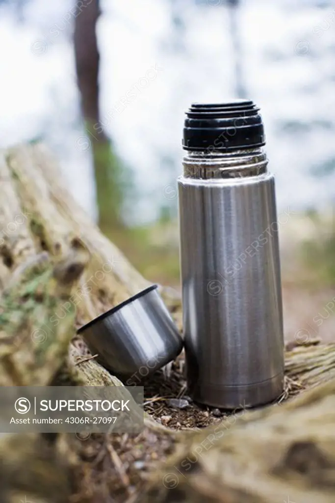 Thermos on forest wood, close-up