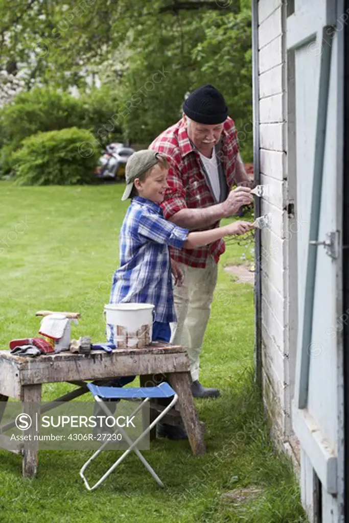 Grandfather and grandson painting their summer cottage, Sweden.