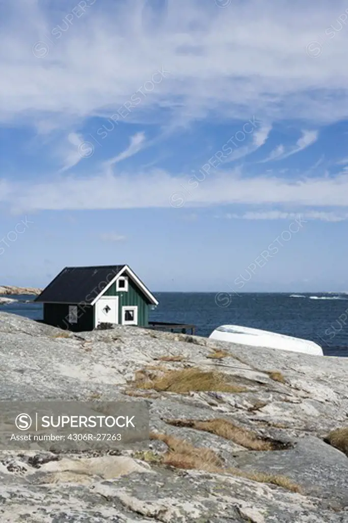 A green cottage and a boat on a cliff, Bohuslan, Sweden.