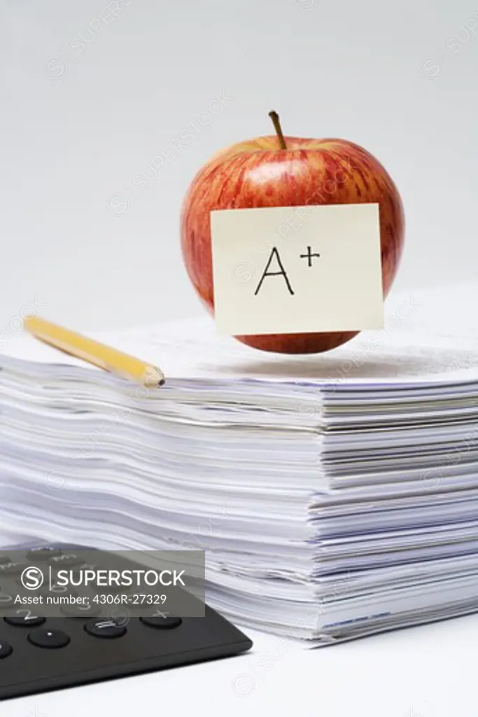 An apple on a stack of paper, close-up.