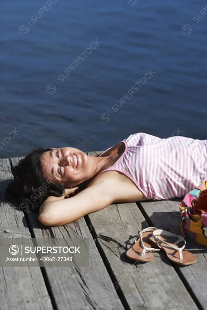 A woman on a jetty by a lake, Sweden.