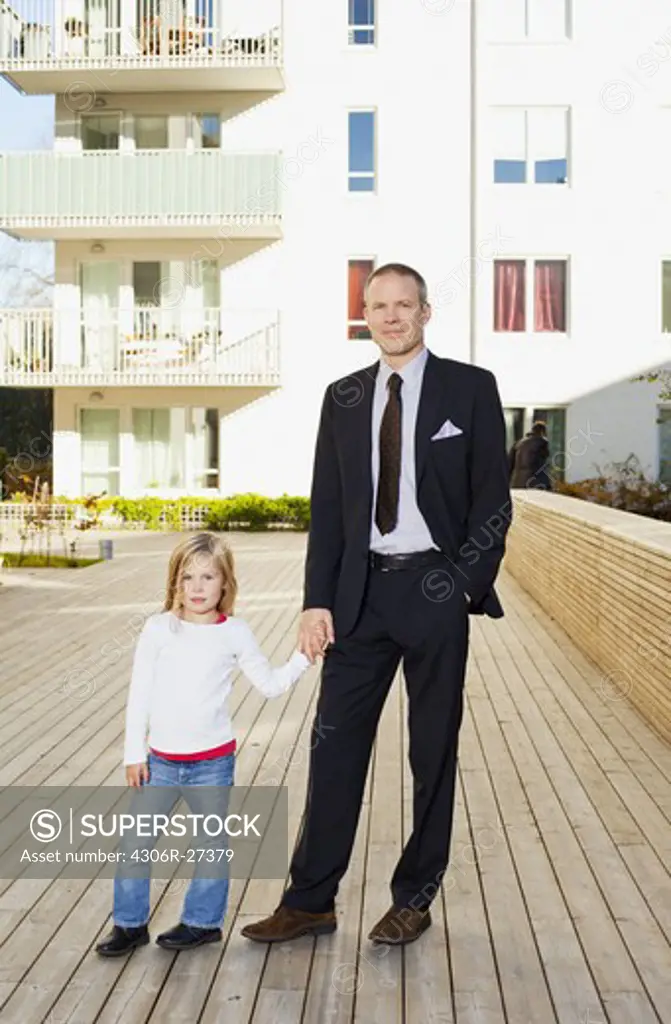 Portrait of father and daughter near apartment building