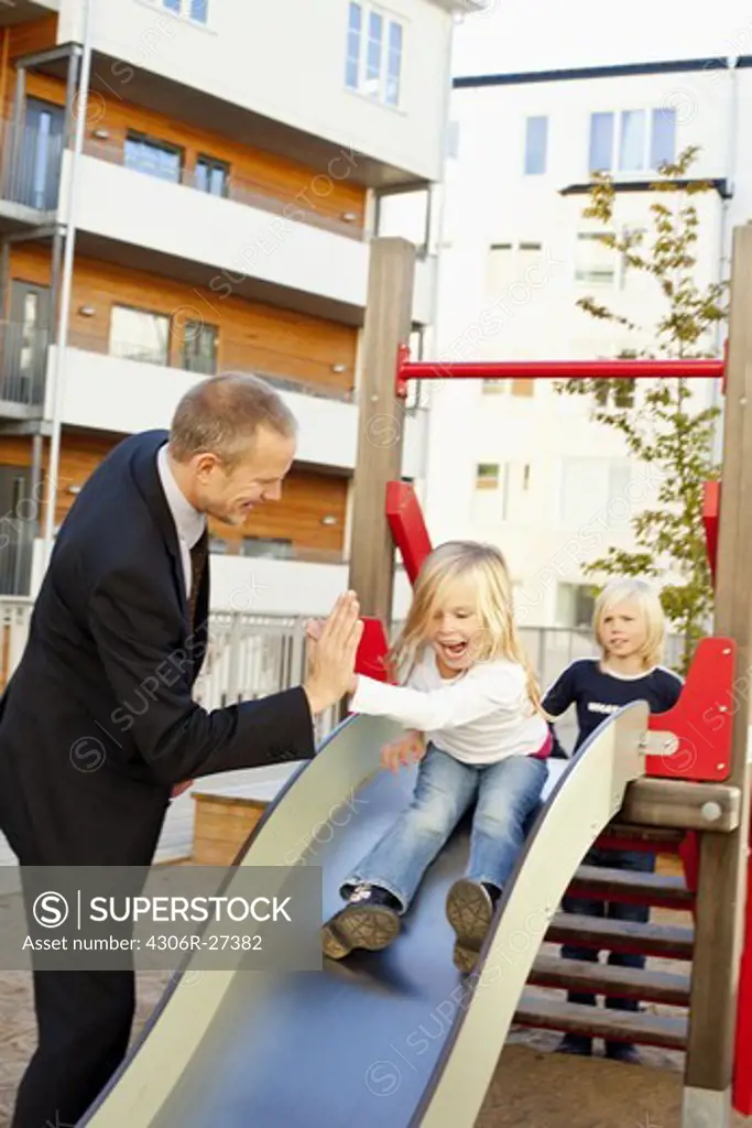 Father and daughters playing on slide