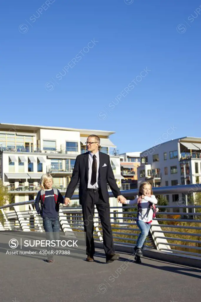 Father and children walking on footbridge
