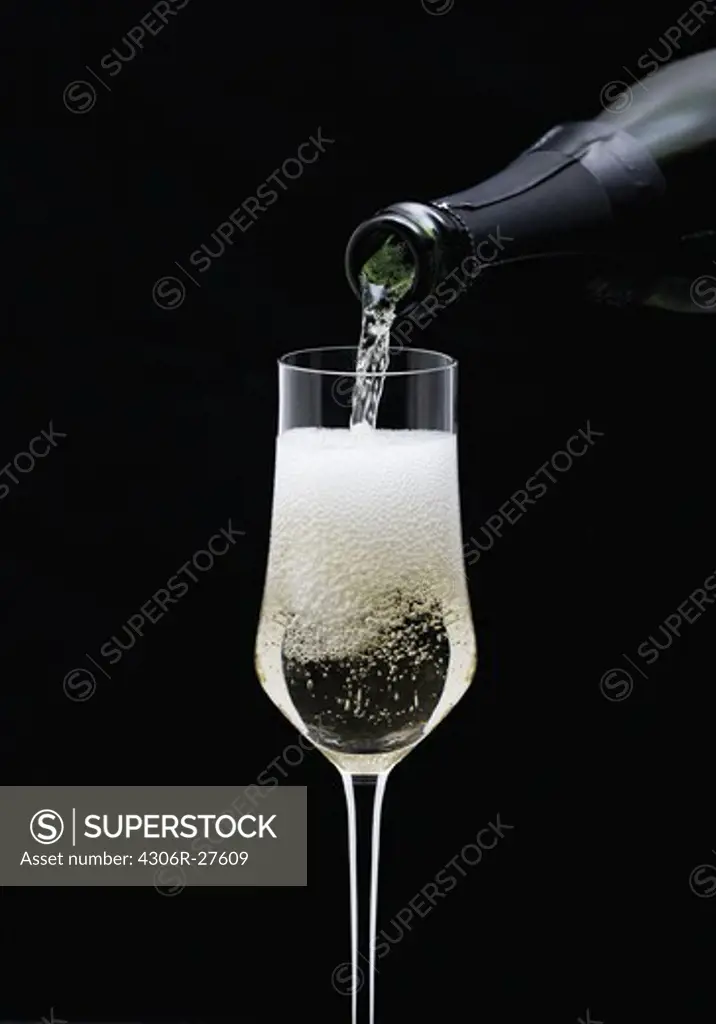 Champagne being pouring into glass from bottle, close-up