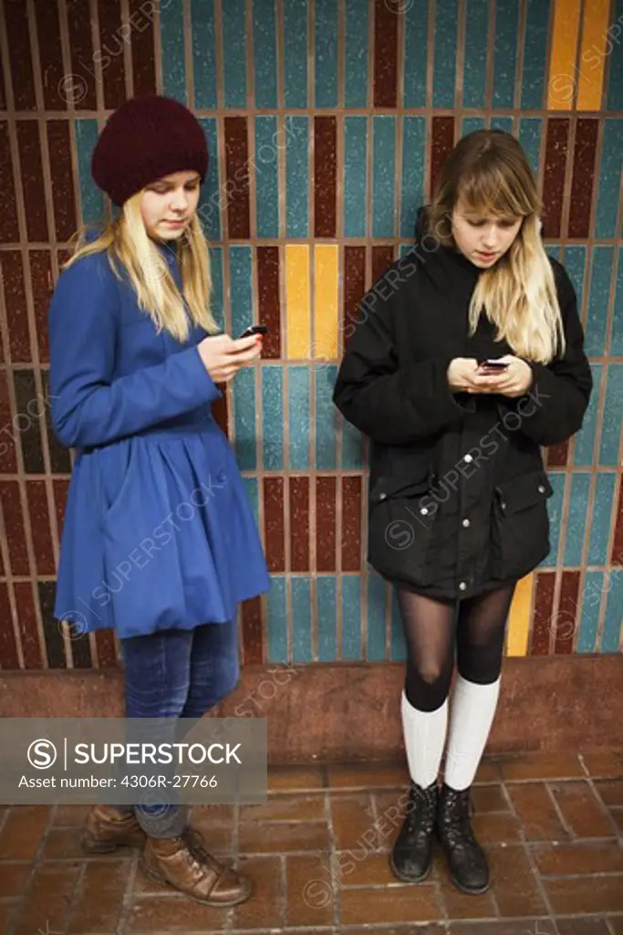 Two teenage girls using cell phones