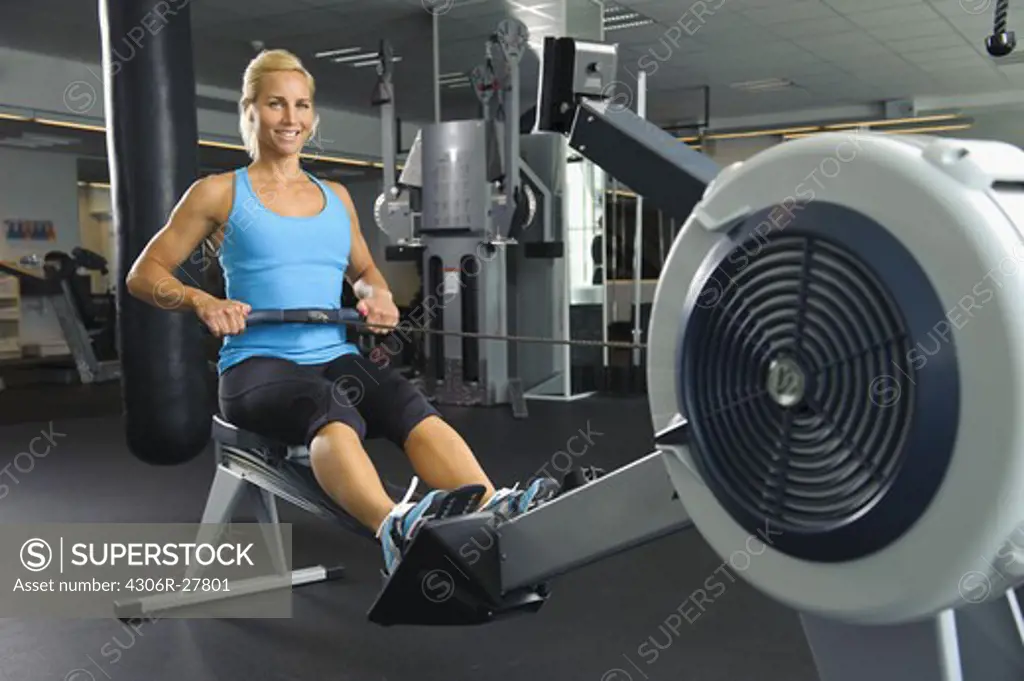 Woman exercising at oarsman in gym
