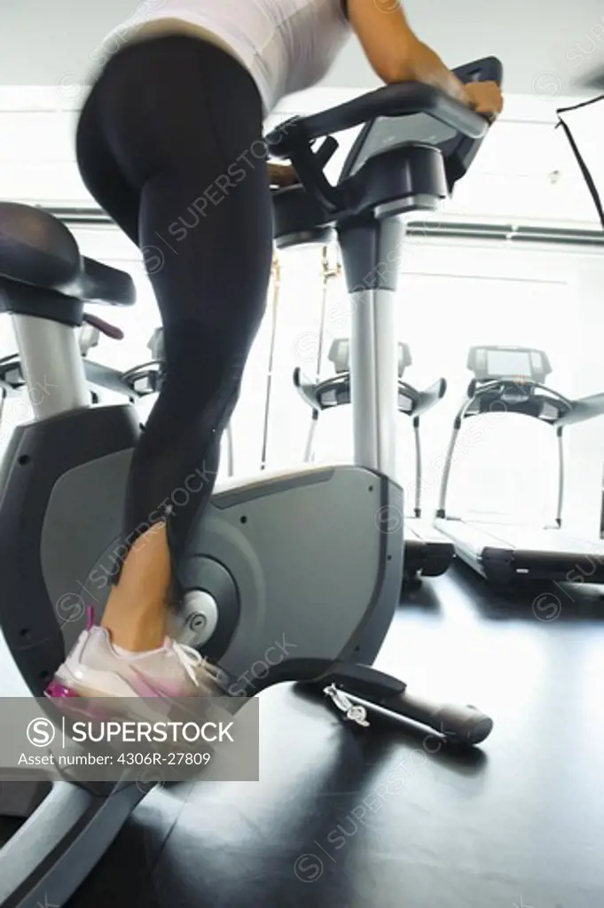 Low section of woman exercising on bike in gym