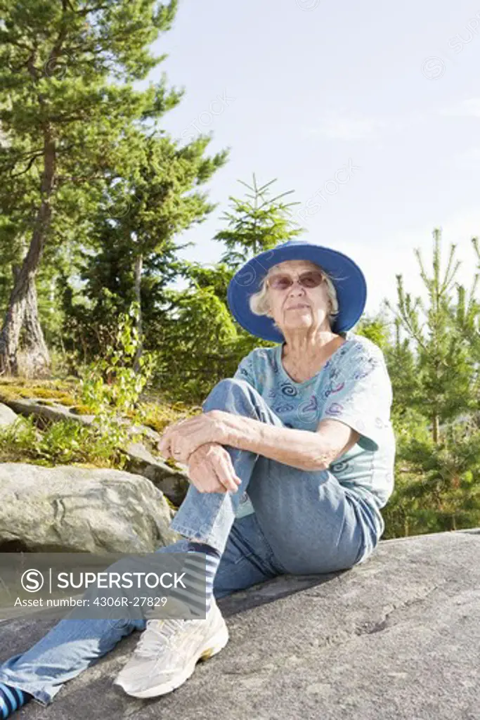 Portrait of senior woman sitting on rock
