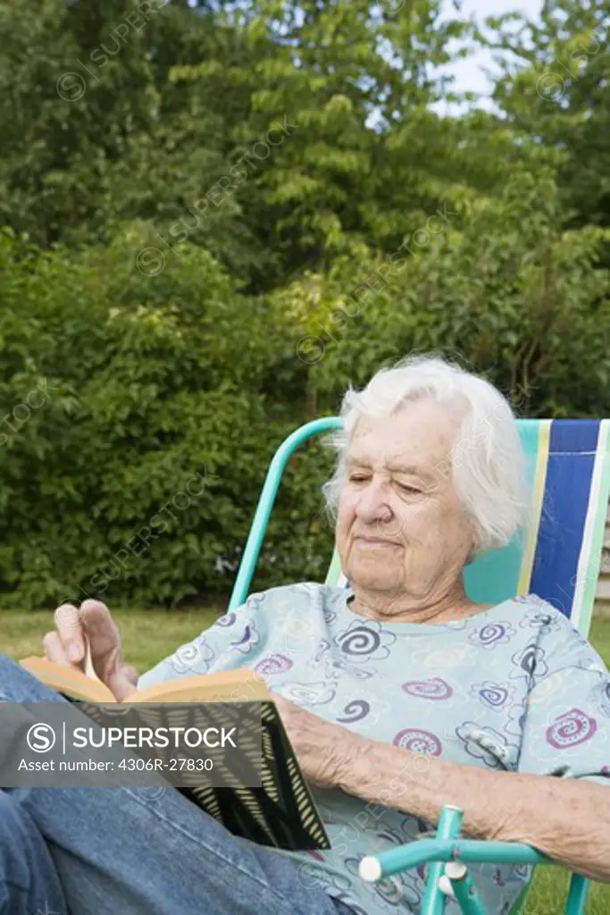 Portrait of senior woman reading book in backyard