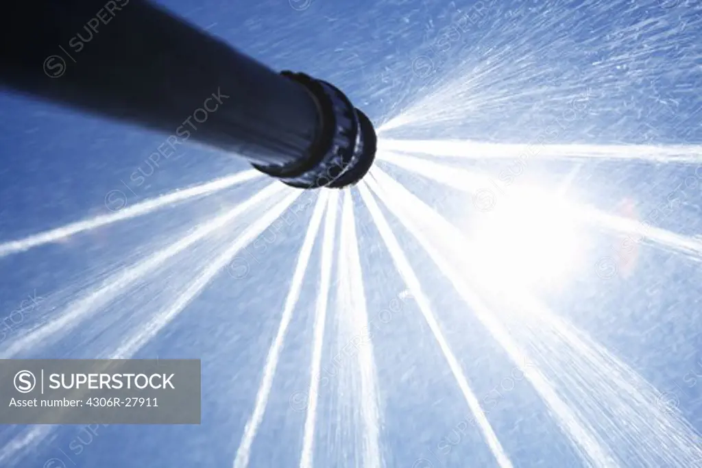 Close-up of sprinkler splashing water under sun