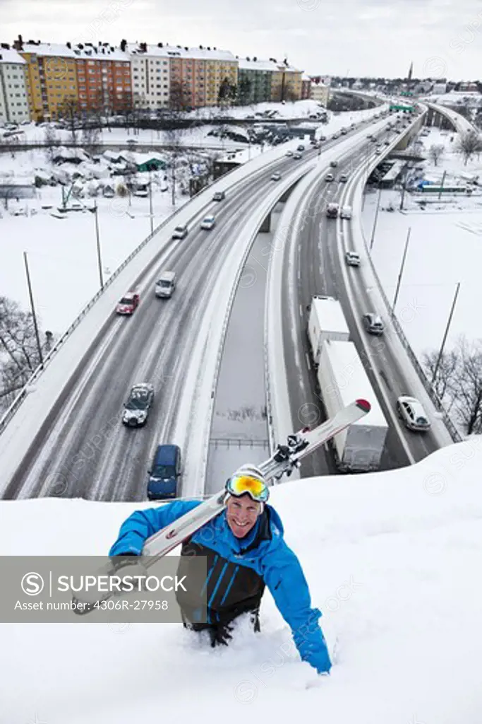 Man holding skies on viaduct above highway