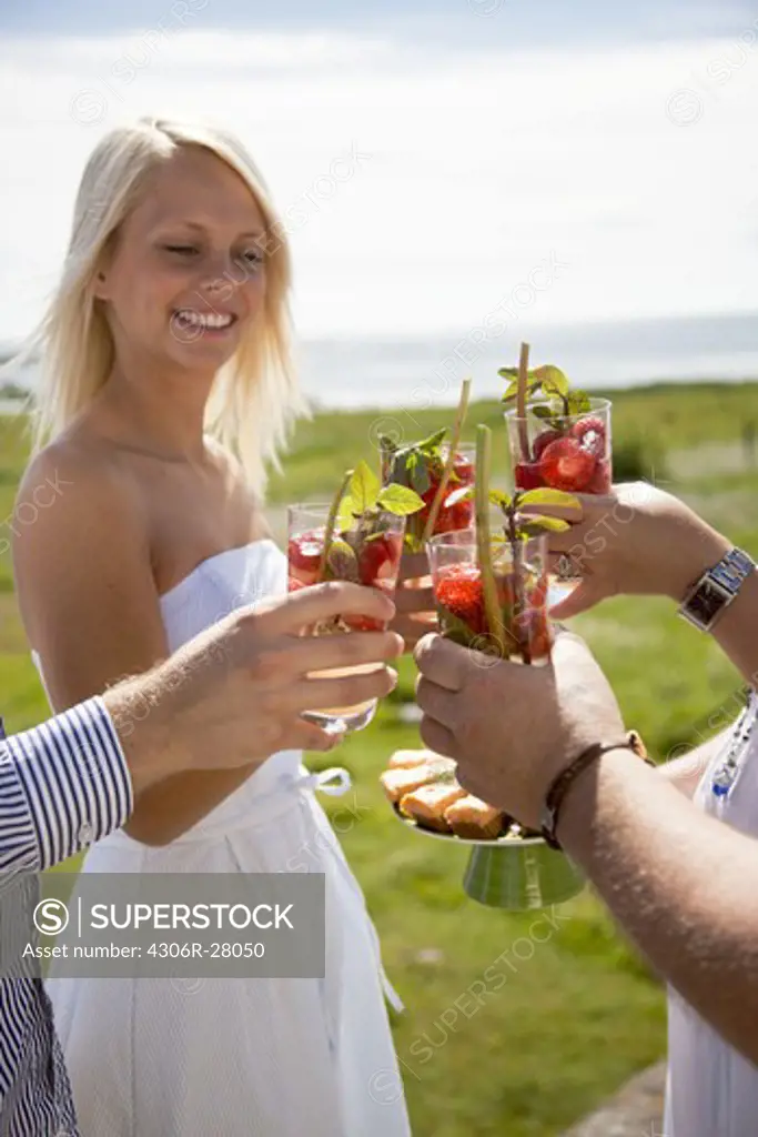 Couples toasting drink at coast, smiling