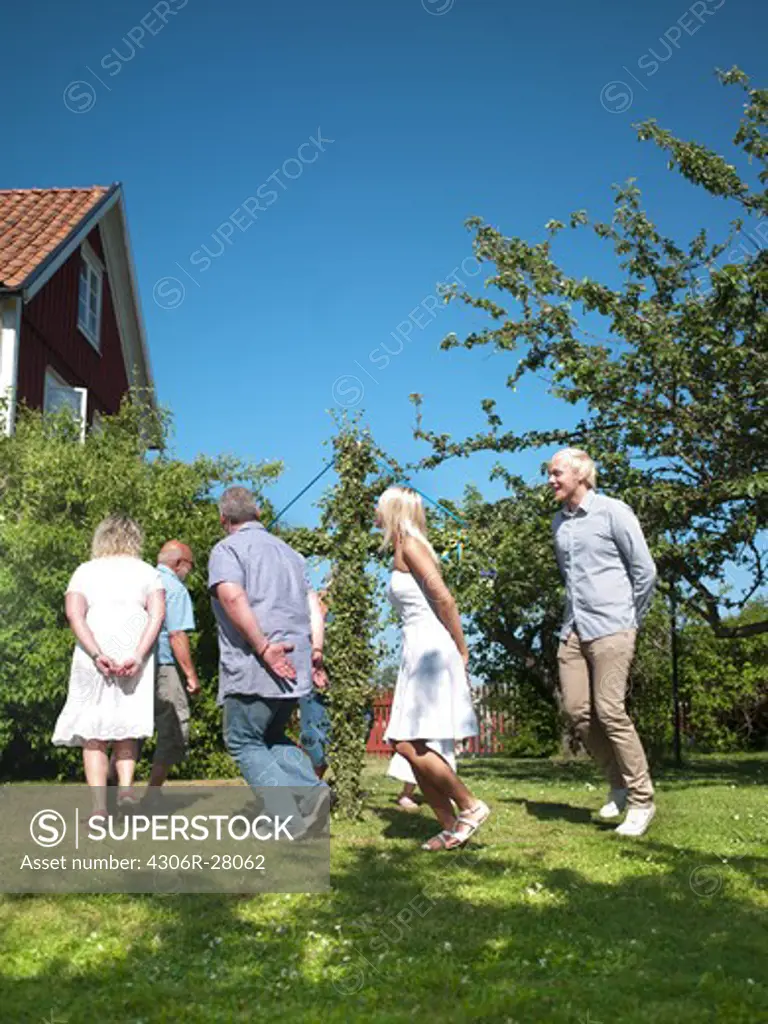 Family dancing around maypole in garden