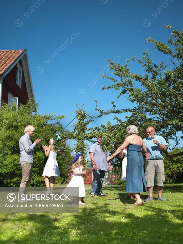 Family dancing around maypole in garden