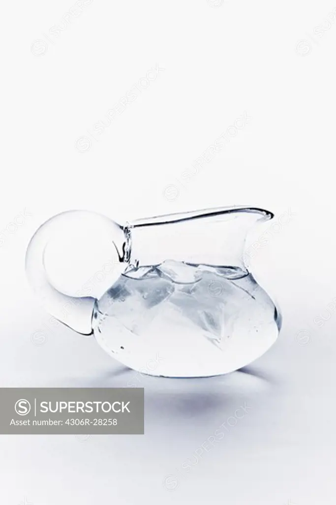 Close up of water with ice cubes in jug on white background