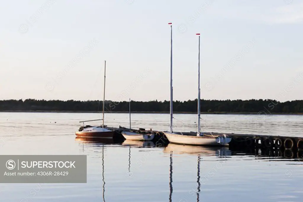 Yachts moored at pier at sunset