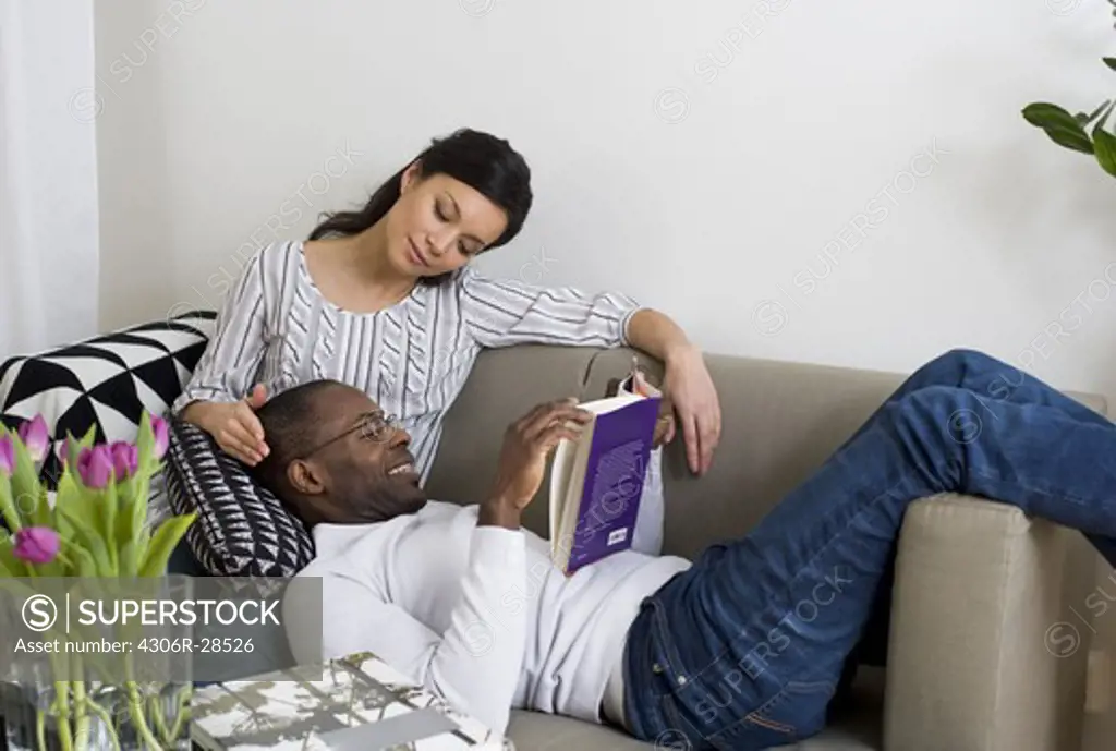 Couple on sofa, man reading book