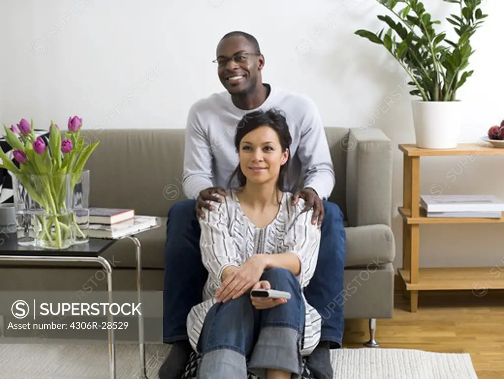 Portrait of couple sitting in living room and watching TV