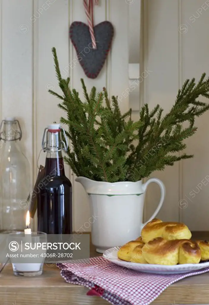 Christmas decoration, bottle of lemonade and saffron roll on table