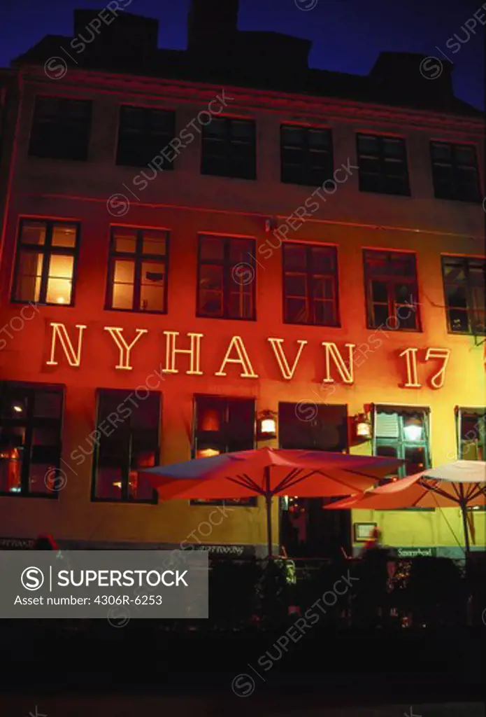 Sign on illuminated building with large umbrellas in foreground