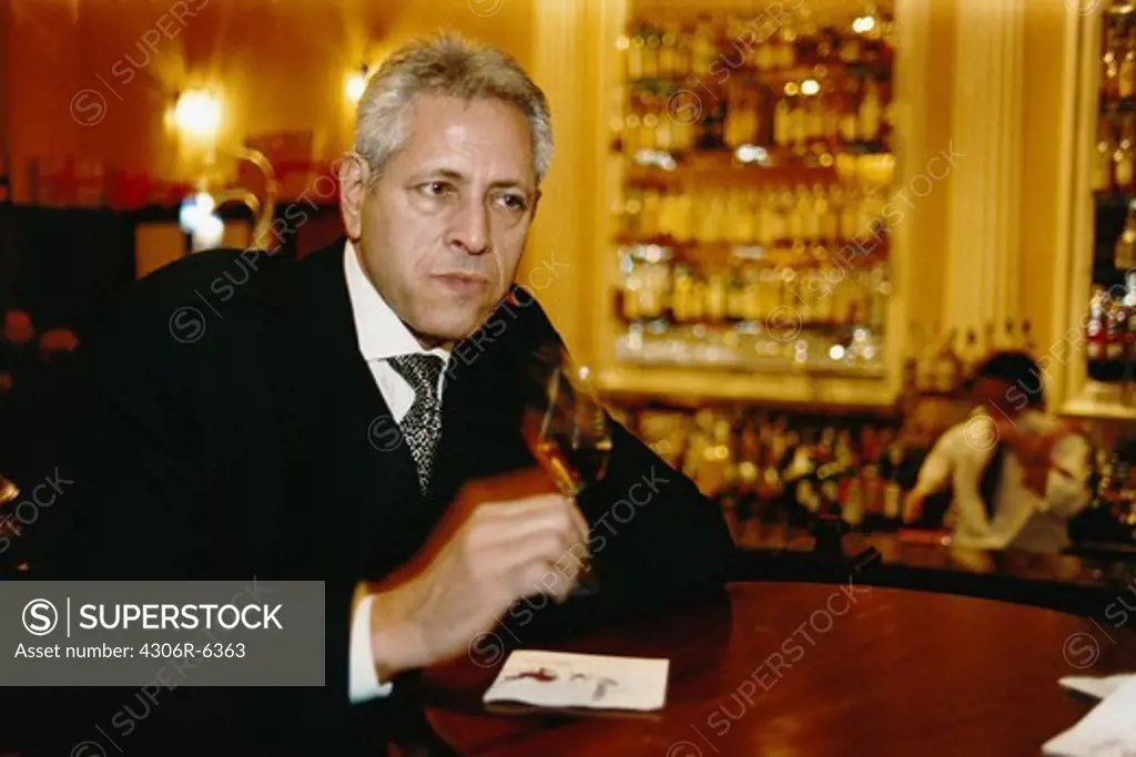 Businessman holding glass of wine in pub