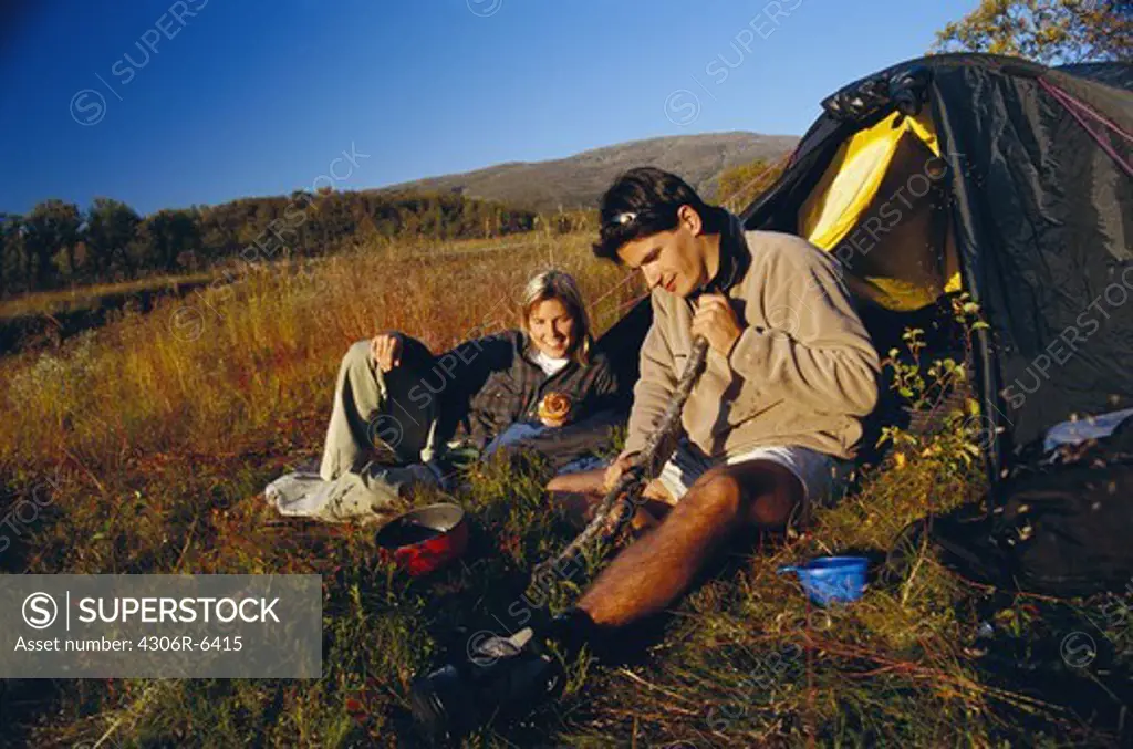 Couple in front of camping tent in field