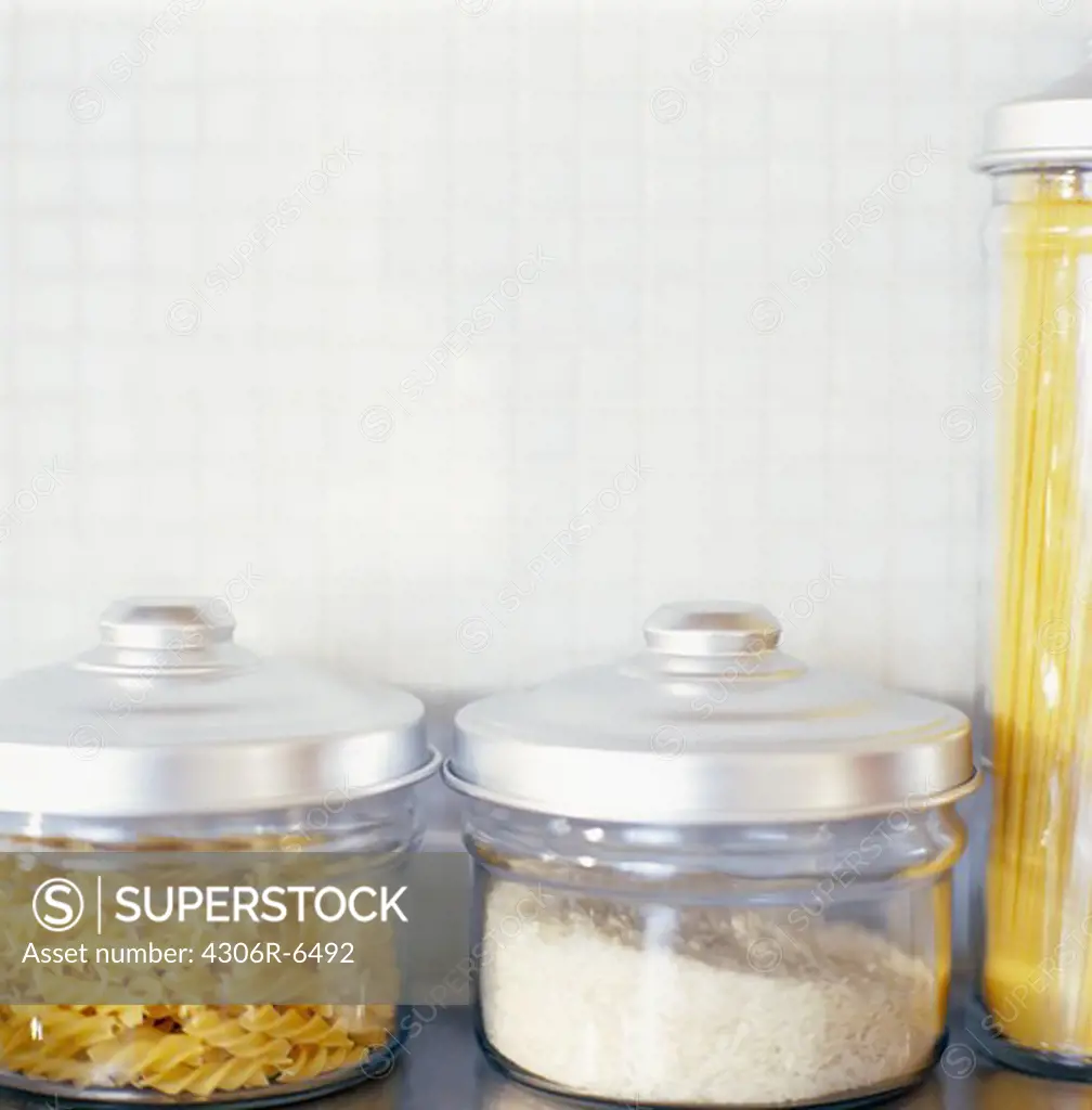 Raw pasta, rice and macaroni in glass jar in domestic kitchen