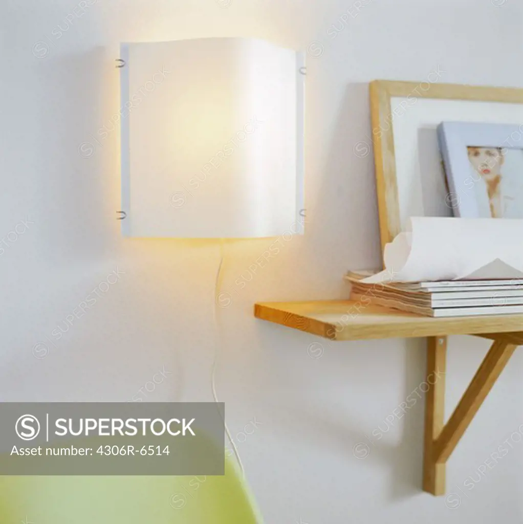 Picture frame on wooden shelf beside illuminated lamp inside home