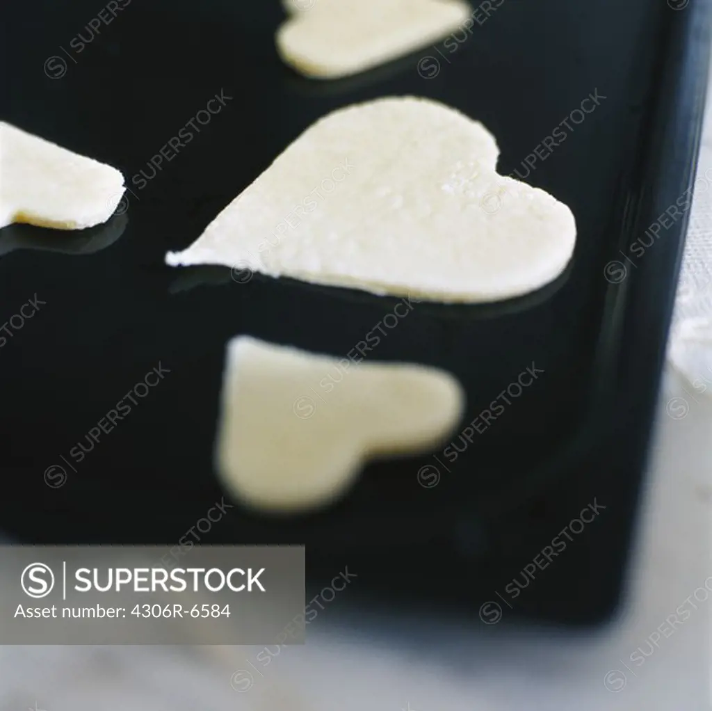 Heart shape cookie dough on black tray