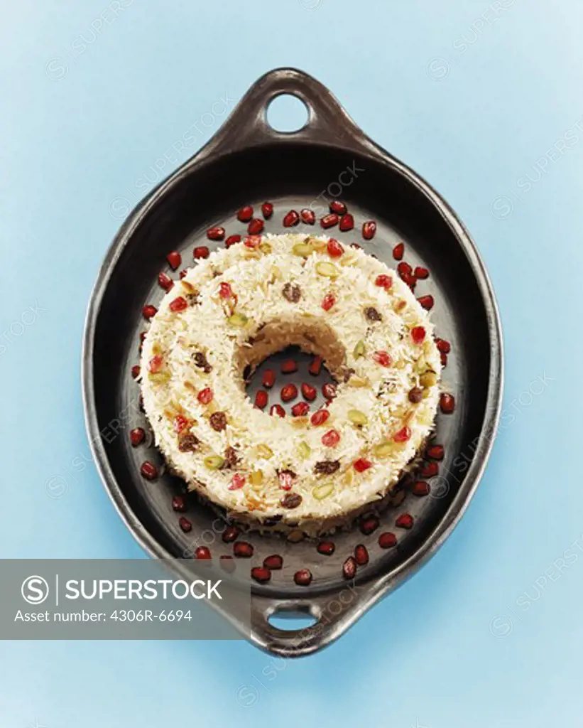 Dessert made of rice and garnished with pomegranate seeds in black pan