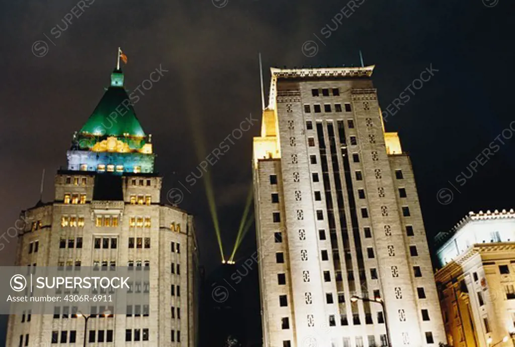 Illuminated buildings at night with beam of light