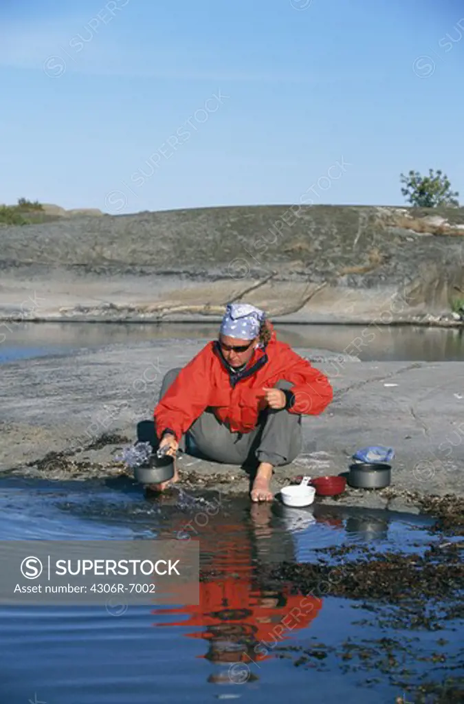 Woman filling pan with water from spring