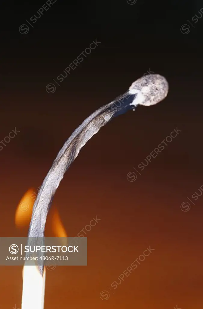 Close-up of flaming match stick against black background
