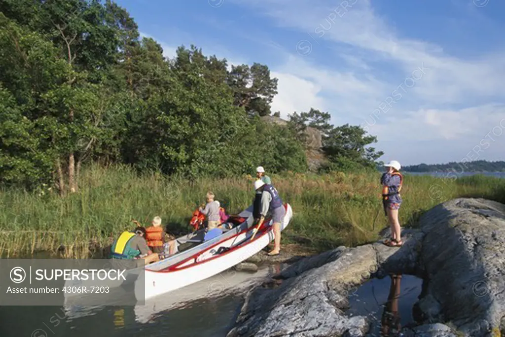 Group of people pulling canoe into land