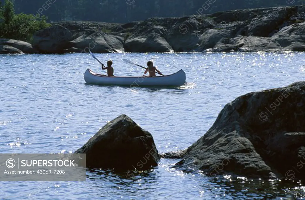 Two children canoeing in river